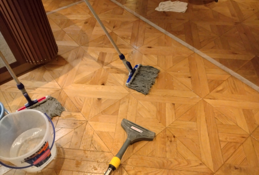 汚水をリンサーで吸い上げ、モップで水拭きをする